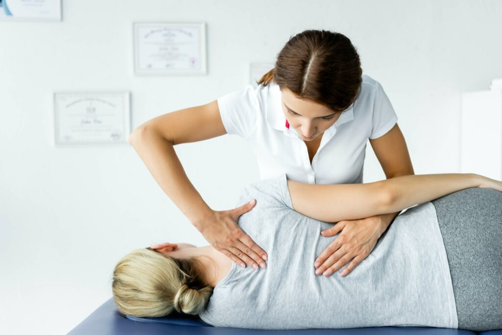 attractive chiropractor touching hand of patient in grey t-shirt