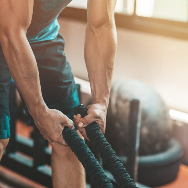 Train more, train harder. Athletic man doing some crossfit exercises with a rope.