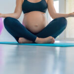 Cropped shot of pregnant woman doing yoga meditation at home