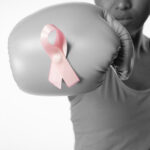 Woman with boxing gloves for breast cancer awareness with ribbon on white background